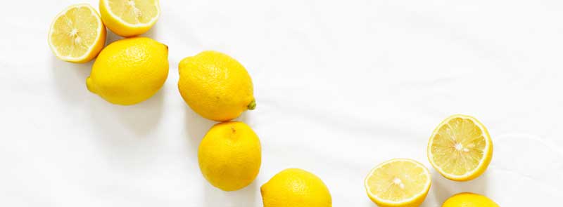 Photographie de citrons entiers et tranchés sur fond blanc