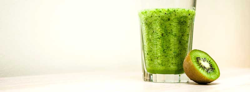 Photographie d'un demi-kiwi cru et d'un verre de smoothie au kiwi