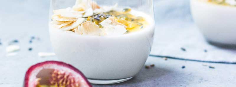 Photographie d'un yaourt nature avec un peu de fruits secs et de fruits de la passion