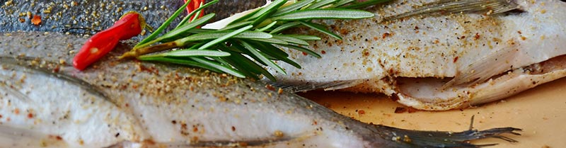 Photographie de poissons en gros plan sur un plan de travail avant leur cuisson, pour illustrer que le poisson est un aliment riche en fer.