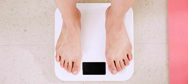 Photographie des pieds d'une femme sur une balance pour mesurer son poids dans le cadre d'un régime amincissant pour perdre du poids.
