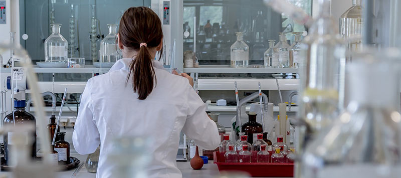 Scientifique prise en photo de dos, en train d'analyser des échantillons dans un laboratoire d'analyse