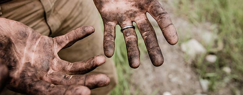 Photographie des deux mains d'un paysans recouvertes de terre après avoir cultivé des aliments bio