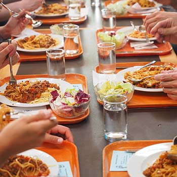 Photographie en couleur d'une table et de plateaux de repas dans les cantines scolaires et la restauration collective.