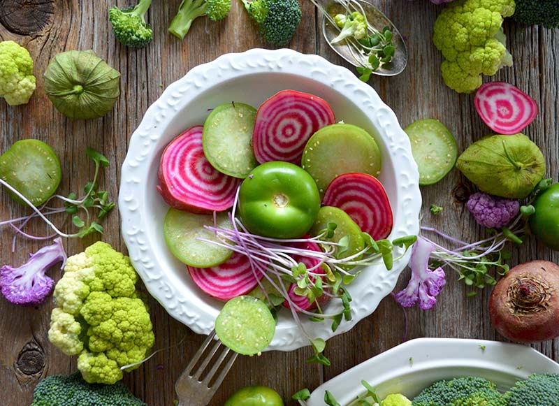 Minéraux, acides aminés, acides gras, tous les oligo-éléments essentiels pour la santé présents dans cette photographie d'une assiette remplie de légumes frais et crus (betterave, poivron, chou-fleur, germes, concombres).