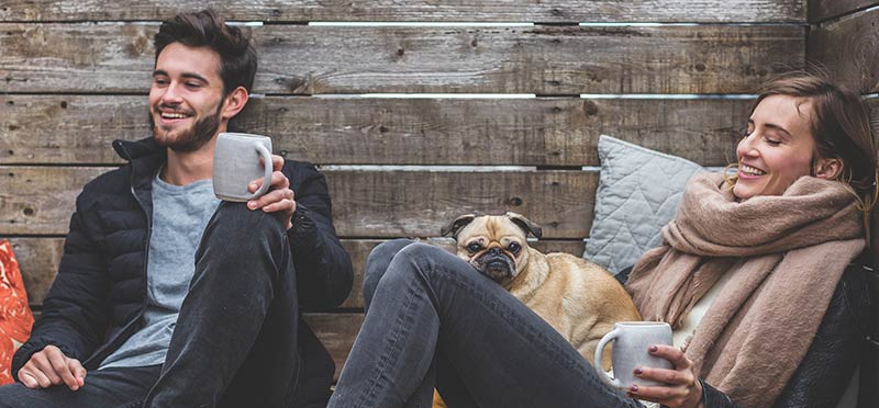 Photo d'un homme, d'une femme et d'un chien buvant un café sur une terrasse