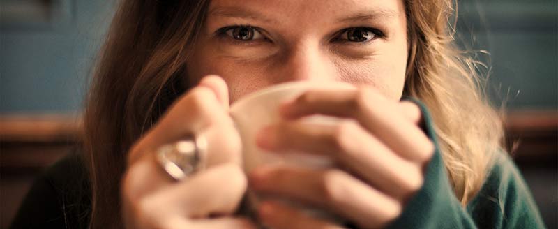 Photographie en gros plan du visage d'une femme buvant une tasse de café