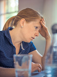 Photographie d'une femme stressée et fatiguée se tenant la tête des les mains en raison d'un manque de magnésium, une carence nutritionnelle causée par un excès de café et de caféine, qui favorise la fuite de magnésium de l'organisme.