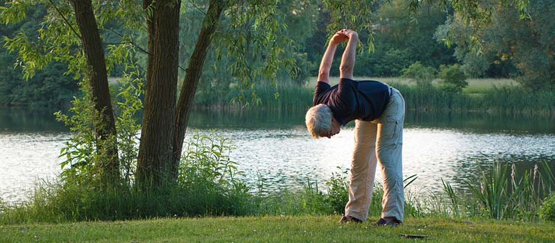 Photographie effectuant des exercices de yoga en plein air afin de lutter contre l'arthrose et retrouver ses mouvements et sa souplesse. Mangez mieux, bougez plus pour dire Stop Arthrose !