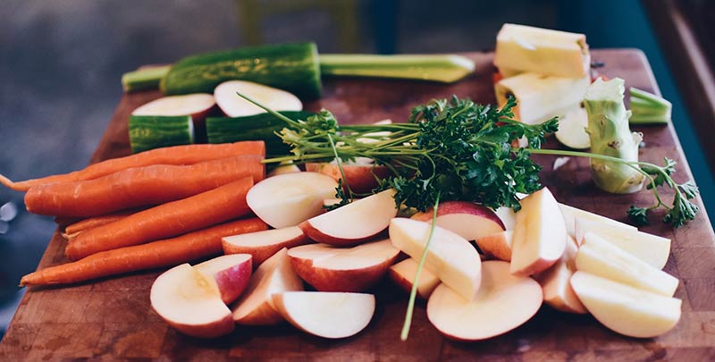 Aliments crus découpés sur une planche en bois : alimentation crue, rawfood, crudivorisme, interview radio sur les dangers de ce régime alimentaire