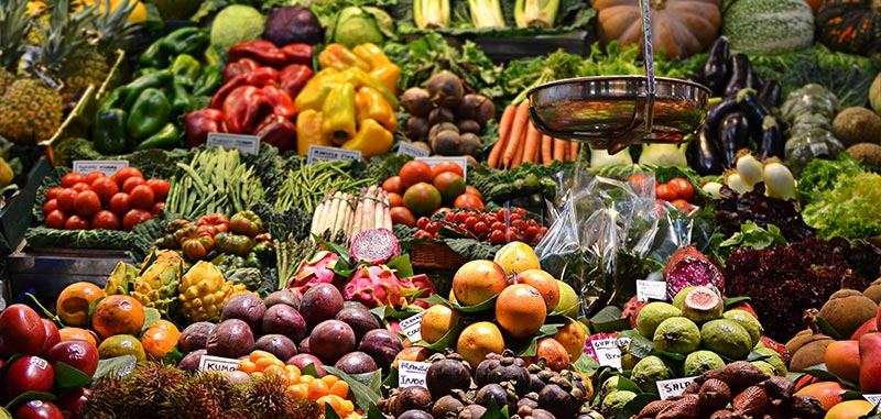 Photographie multicolore de l'étalage magnifique d'un primeur très bien achalandé avec de nombreux fruits et légumes variés. Manger équilibré est primordial en micronutrition.