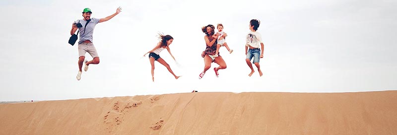 Micronutrition : famille heureuse qui saute au sommet d'une dune de sable pour montrer son bonheur et sa bonne santé.